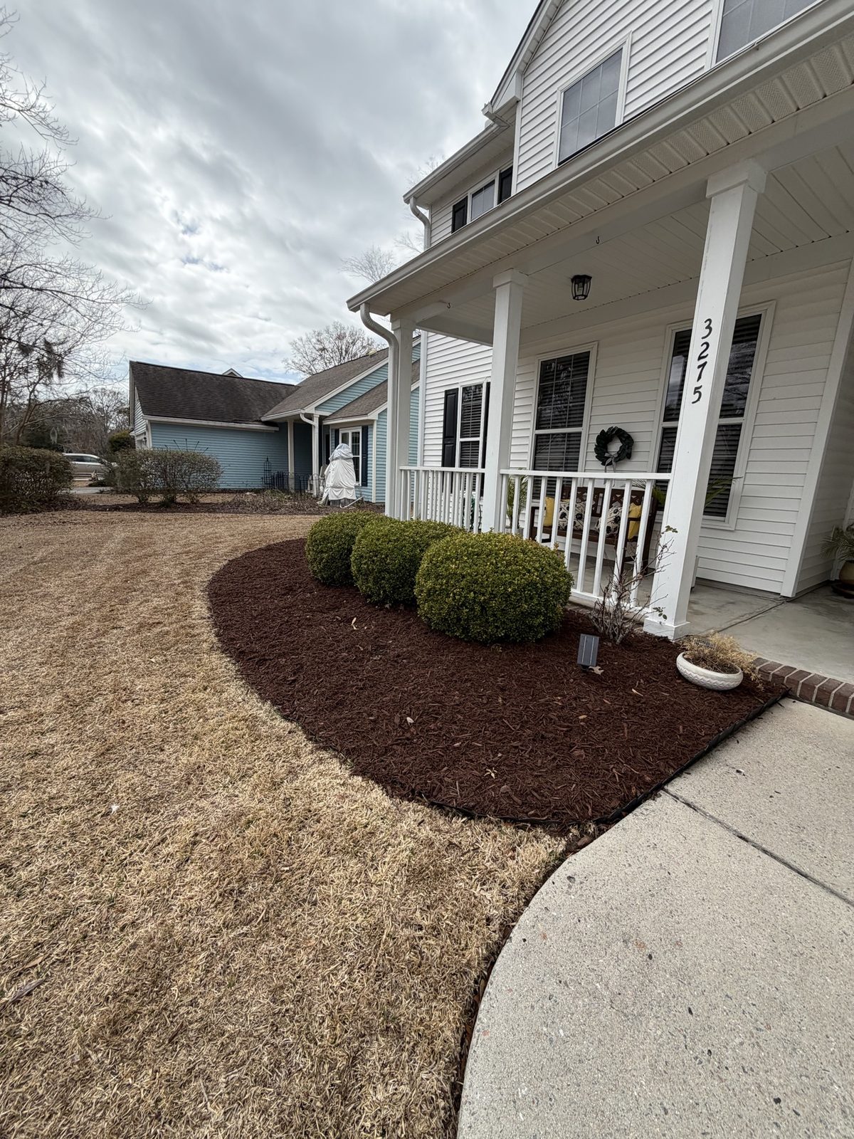 Curved mulch bed with trimmed shrubs in front of a home entrance