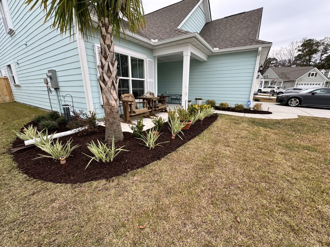 New mulch bed with fresh plantings beside a coastal home